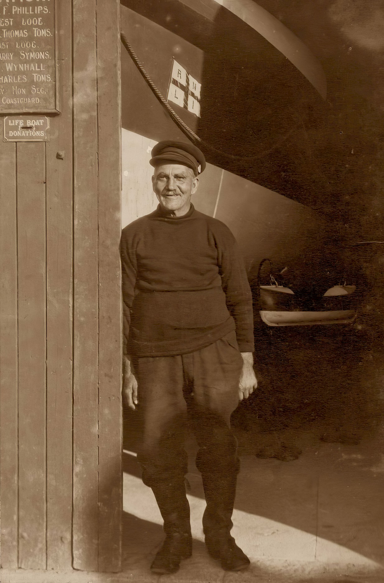 W Thomas Toms smiles while leaning against the door of the lifeboat house